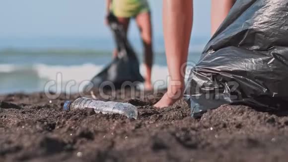 群志愿者清理沙滩志愿者举起一个塑料瓶扔进袋子里志愿服务和视频的预览图
