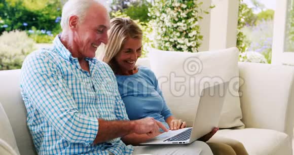 年长夫妇在客厅使用笔记本电脑时相互交流视频的预览图