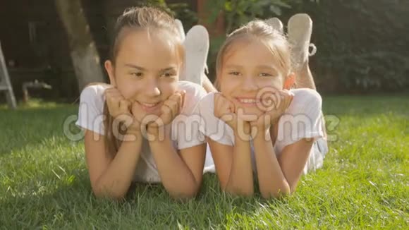 两个少女在阳光明媚的夏日躺在草地上的肖像视频的预览图