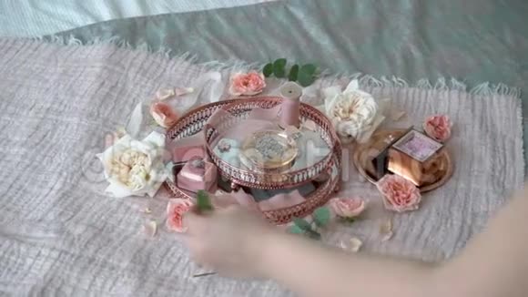 女人把花放在粉红色的托盘上上面有新娘耳环求婚戒指和香水视频的预览图