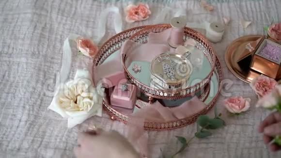 女人把花放在粉红色的托盘上上面有新娘耳环求婚戒指和香水视频的预览图