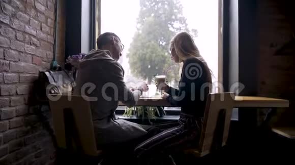 一个女孩和一个男人在咖啡馆里度过美好的时光而外面下雨视频的预览图