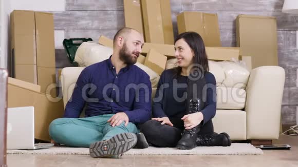 漂亮的年轻夫妇坐在他们新公寓的地板上视频的预览图