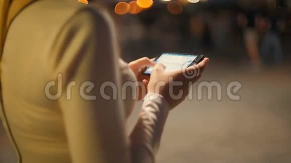晚上在拥挤的街道上一位优雅的年轻在夜间打字视频的预览图