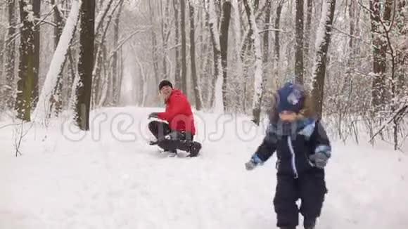 爸爸儿子和妈妈在冬天公园玩雪球视频的预览图