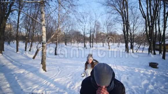 男人和女人的一对夫妇在一片白雪皑皑的冬林里互相扔雪球慢动作视频的预览图