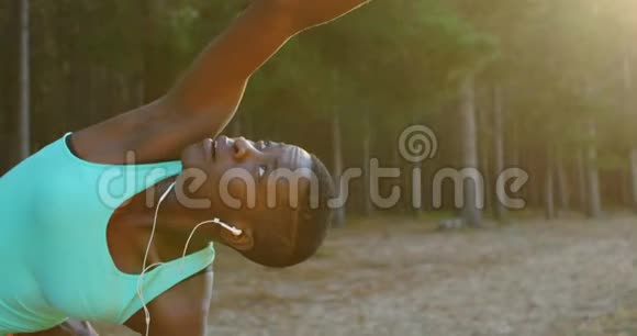 女运动员在森林里听音乐时做伸展运动视频的预览图
