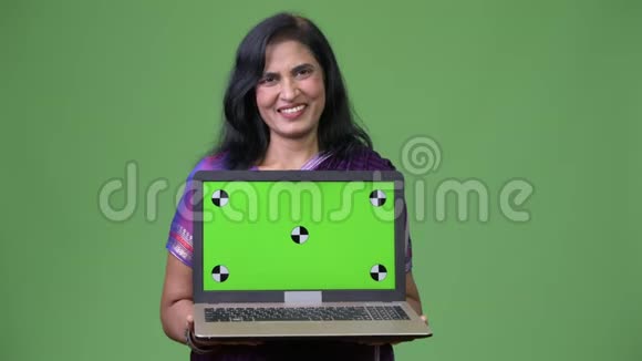 成熟快乐美丽的印度女人微笑着展示笔记本电脑视频的预览图