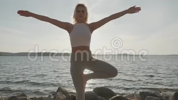 日落时在海上冥想的女孩健身和健康的生活方式瑜伽练习视频的预览图