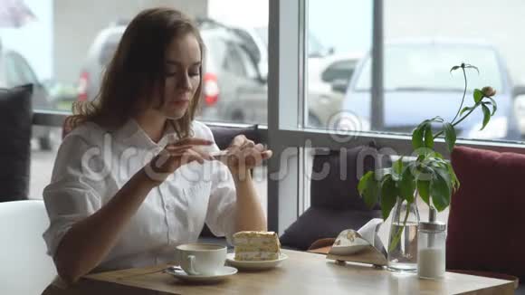 女孩在手机摄像头上为一个流行的社交网络拍照咖啡和蛋糕视频的预览图