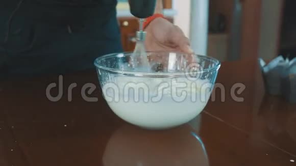 在厨房的桌子上用搅拌器在玻璃碗里做奶油视频的预览图