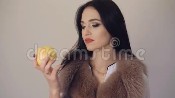 可爱的女孩吃着一个又大又多汁的苹果微笑着调情背景是4K视频的预览图