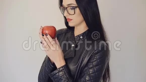 戴眼镜的漂亮女孩拿着红色多汁的苹果背景是4K视频的预览图