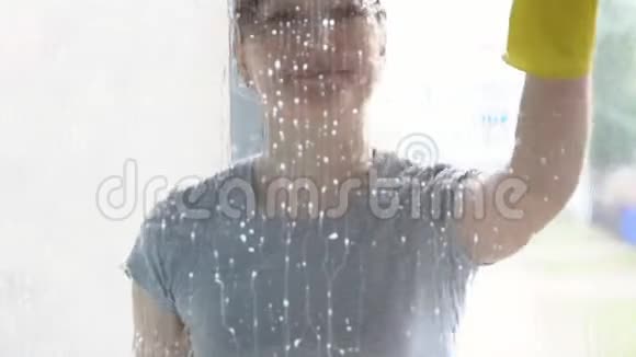 美丽的女人用蓝色的抹布和清洁剂洗窗户视频的预览图