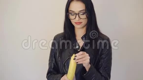 戴眼镜的可爱女孩剥着一根大香蕉对着镜头微笑视频的预览图
