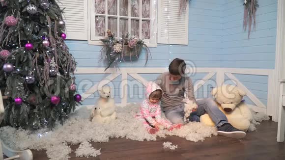 父亲带着一个小女儿坐在树下扔雪视频的预览图