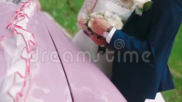 一对漂亮的新婚夫妇拥抱粉色复古车视频的预览图