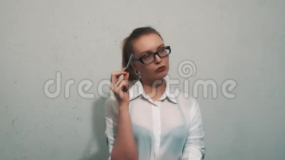 穿着白衬衫的无聊女人用扩耳机把笔折在头上视频的预览图