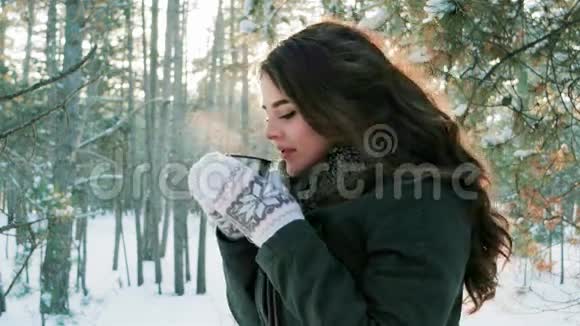 年轻女子在冬林里喝茶美丽的女孩在冬天在户外喝茶可爱的女孩拿着杯子视频的预览图