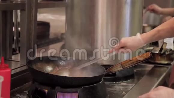 在餐厅的厨房里人们在热炒炒锅上搅动蔬菜和肉视频的预览图
