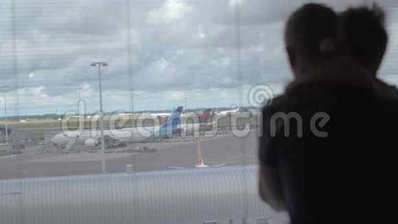 在荷兰阿姆斯特丹的飞机跑道上母亲和儿子站在窗口观看的背面景色视频的预览图