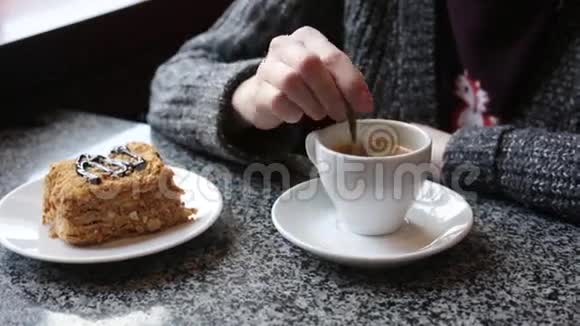 那个女孩在一杯白咖啡里搅拌糖女性手拿着一杯美式浓缩咖啡视频的预览图
