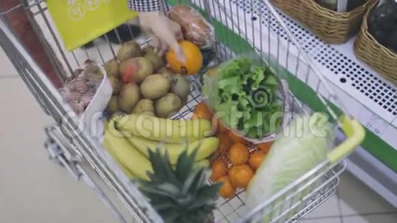 带着购物车的女孩拿起蔬菜和水果视频的预览图