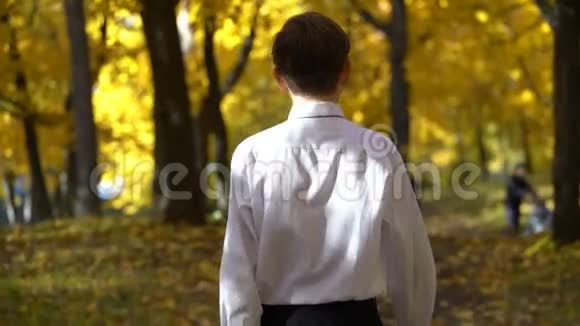 穿着白色衬衫在秋天公园散步的年轻人视频的预览图