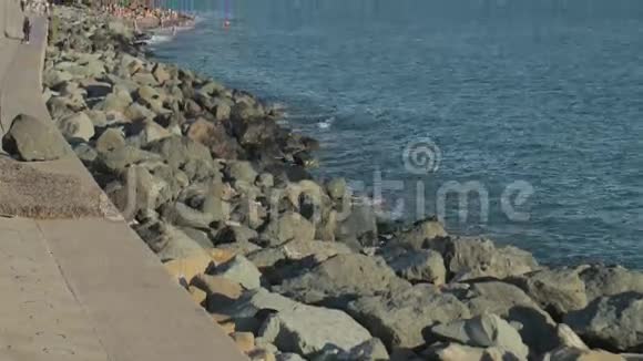 缓慢倾斜的岩石海岸与海滩和游客视频的预览图
