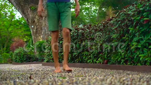 一个年轻人在热带公园的反射路径上慢镜头视频的预览图