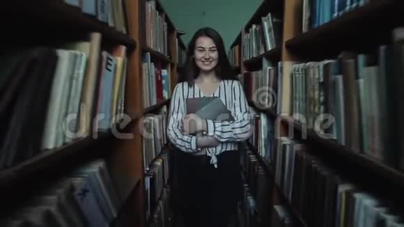 一个留着长长黑发的漂亮女孩在图书馆的书架之间视频的预览图