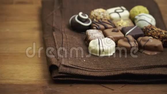 手工制作的巧克力糖果落在木制背景上慢动作的美味糖果视频的预览图