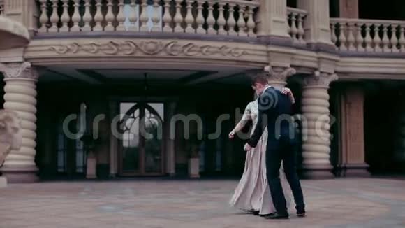 优雅的一对年轻人在皇宫的背景下在一个女孩的手中盘旋视频的预览图
