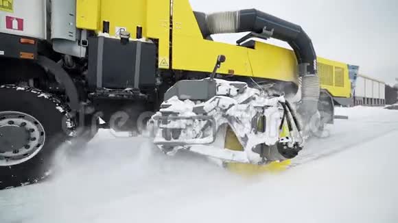 在下雪的天气里重型车轮机械用巨大的旋转刷子从道路上清除雪特殊的机械视频的预览图