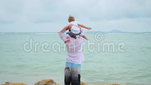 一个年轻人在海滨抱着一个孩子幸福家庭视频的预览图