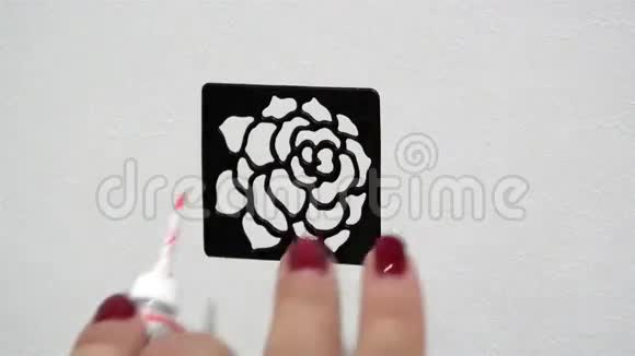 在一个女人的手在白色背景上的黑色模板上画出红色油漆的轮廓视频的预览图