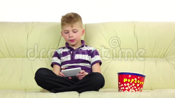 男孩玩电话在线游戏吃爆米花慢动作视频的预览图