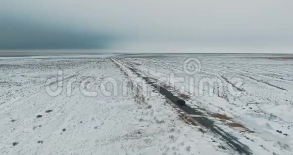 黑车在雪林的冬季乡间小路上行驶从无人驾驶飞机上俯瞰空中景色视频的预览图