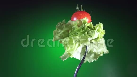 用新鲜的红番茄叉在水滴里生菜旋转绿色背景视频的预览图