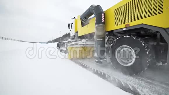 在下雪的天气里重型车轮机械用巨大的旋转刷子从道路上清除雪特殊的机械视频的预览图