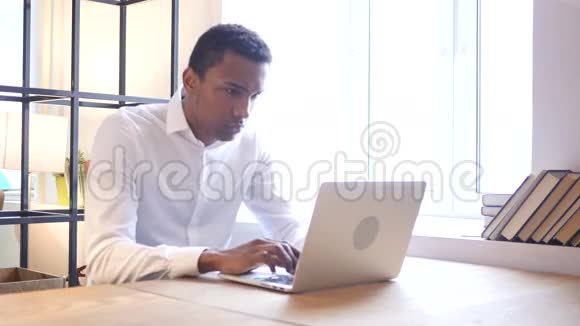 焦虑不安的黑人在笔记本电脑上工作视频的预览图