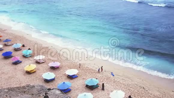 空中无人机观看热带海滩海滩上有雨伞和甲板椅印度尼西亚巴厘慢动作3840x2160视频的预览图