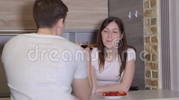 年轻夫妇在一张有葡萄酒和草莓的桌子上浪漫的夜晚视频的预览图