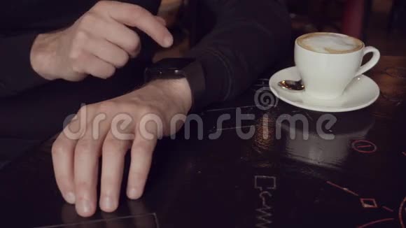 在小咖啡馆的咖啡杯附近用智能手表近距离拍摄人的手视频的预览图