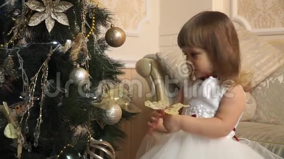穿着节日礼服的小女孩在圣诞树旁有一只金色的蝴蝶视频的预览图
