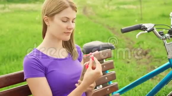 在公园热的时候女人在手机上使用便携式呼吸机用小风扇冷却视频的预览图