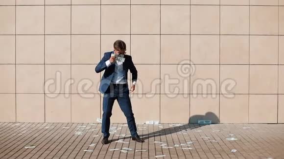 年轻快乐的商人把钱撒在街上跳舞它位于办公中心附近慢动作视频的预览图