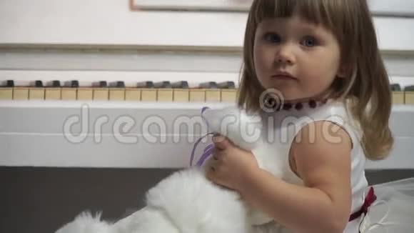 一个小女孩在钢琴背景下用玩具狗特写视频的预览图