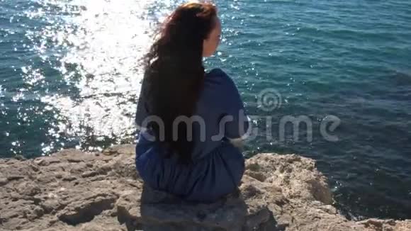 女孩坐在悬崖边的大风中视频的预览图