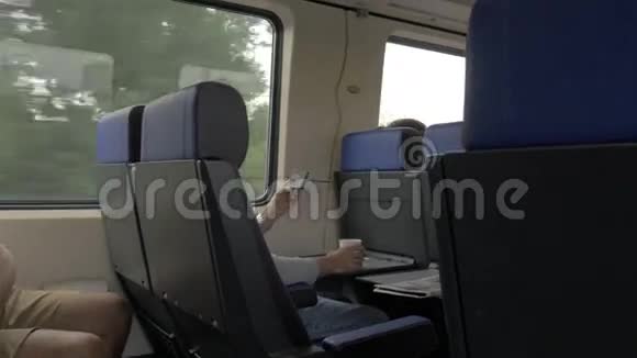 在火车上和桌上的笔记本电脑和靠窗喝酒的男人的看法荷兰视频的预览图
